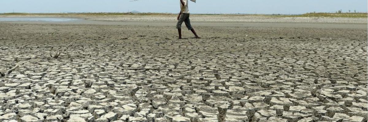 A man walks over the parched bed of a reservoir on the outskirts of Chennai, India on May 17, 2017. (Photo: Arun Sankar/AFP via Getty Images)