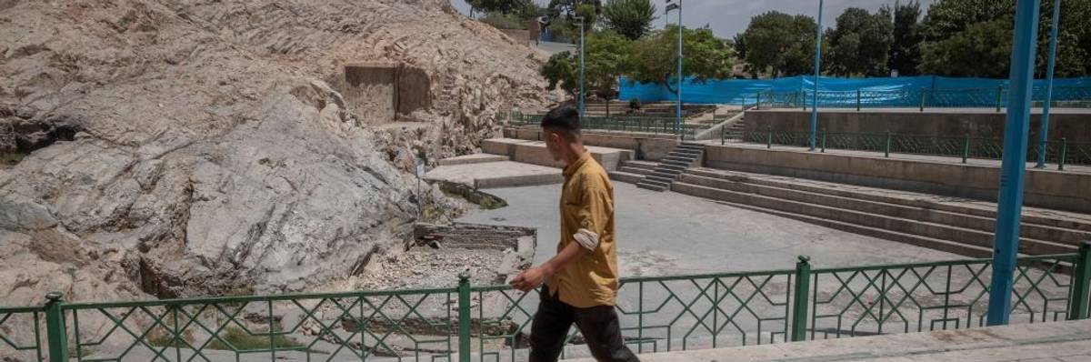 A man walks past a dried-up fountain in Tehran.