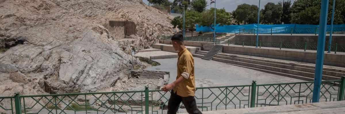 A man walks past a dried-up fountain in Tehran.