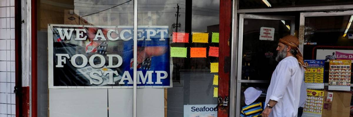 A man with a gray beard looks at a sign reading, "We accept food stamps."