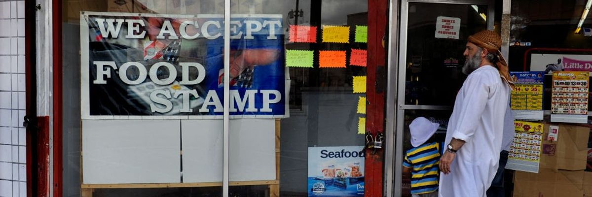 A man with a gray beard looks at a sign reading, "We accept food stamps."