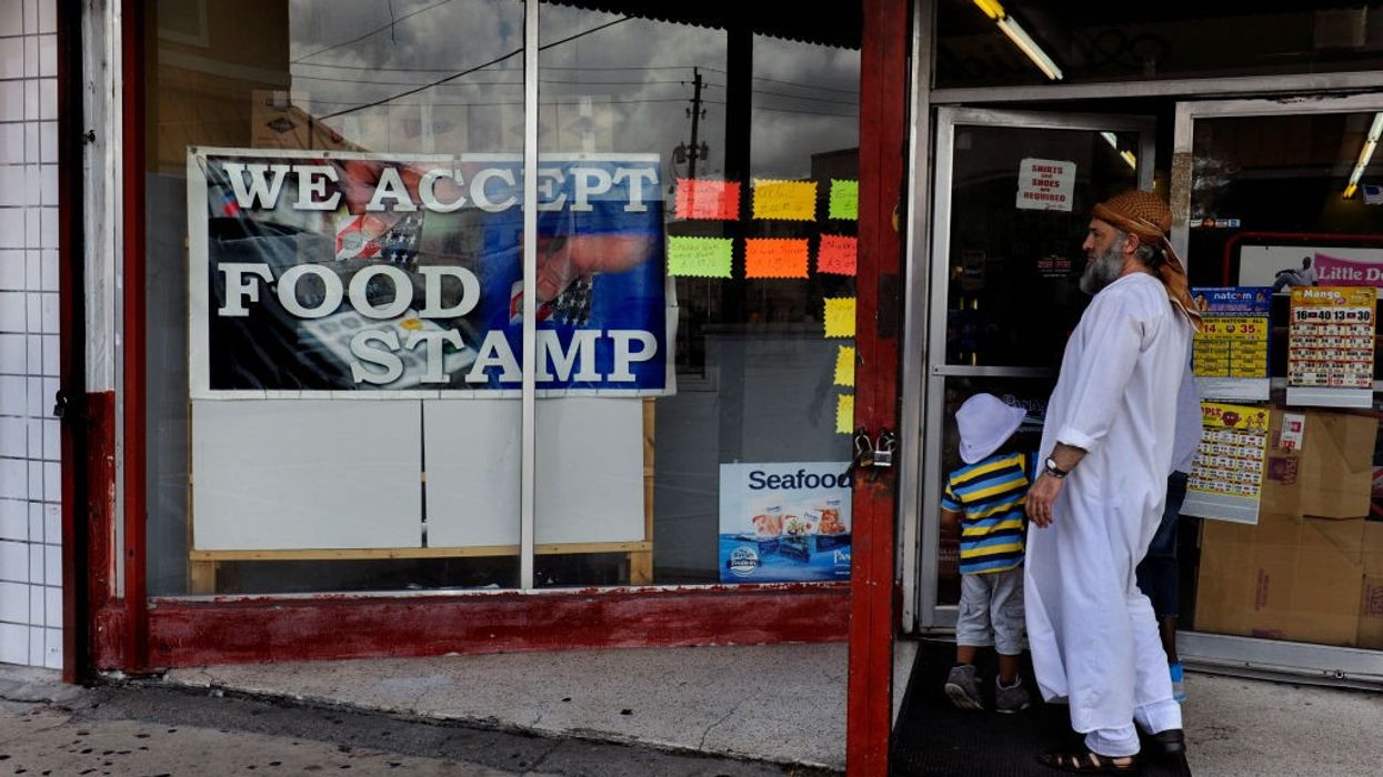 A man with a gray beard looks at a sign reading, "We accept food stamps."