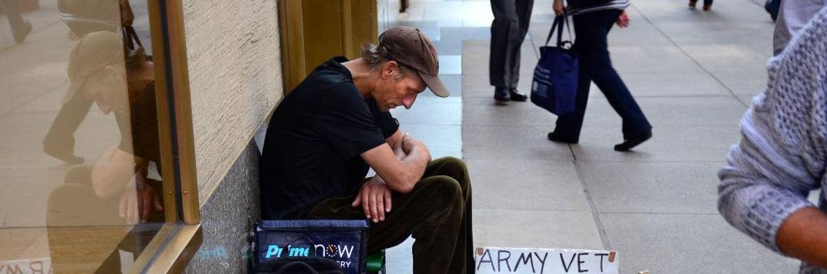 A man with a sign identifying himself as a homeless Army veteran asks for money as he sits on a New York City sidewalk.