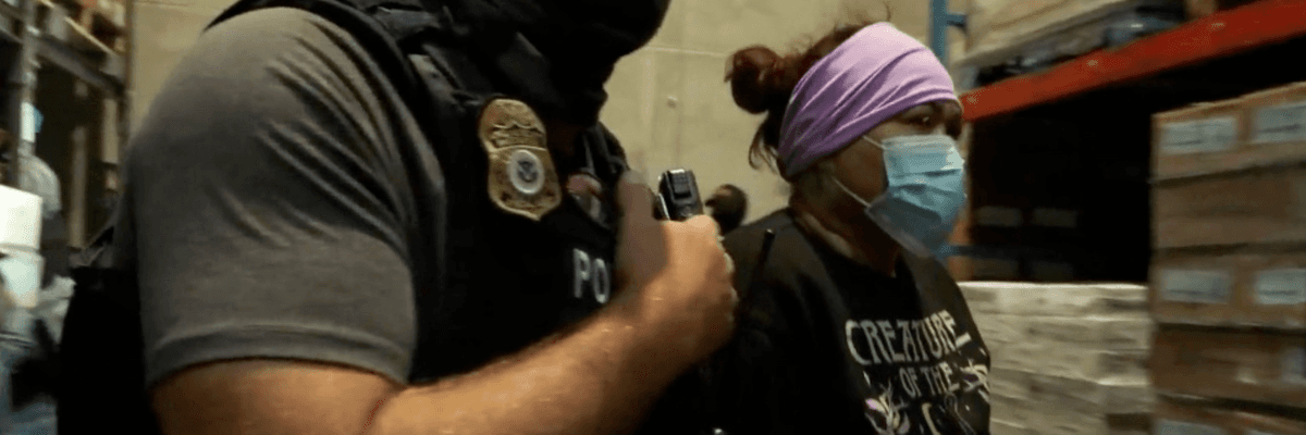 A masked ICE agent arrests a woman