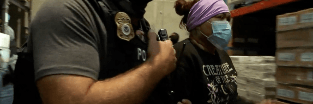A masked ICE agent arrests a woman