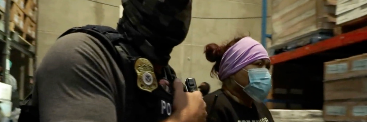 A masked ICE agent arrests a woman