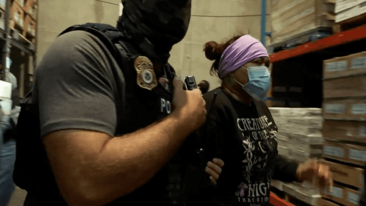A masked ICE agent arrests a woman