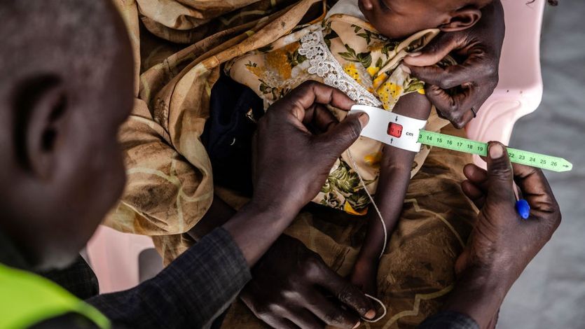 A medical worker measures the cirumference of a Sudanese child's arm.