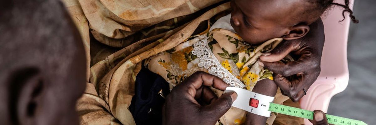 A medical worker measures the cirumference of a Sudanese child's arm.
