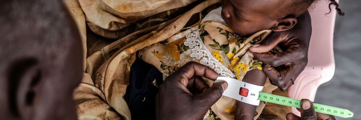 A medical worker measures the cirumference of a Sudanese child's arm.