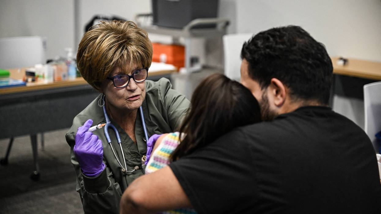A member of the medical staff administers a dose of the measles vaccine