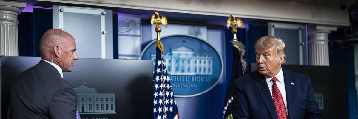 A member of the Secret Service speaks to then-President Donald Trump at the White House on August 10, 2020 in Washington, D.C.