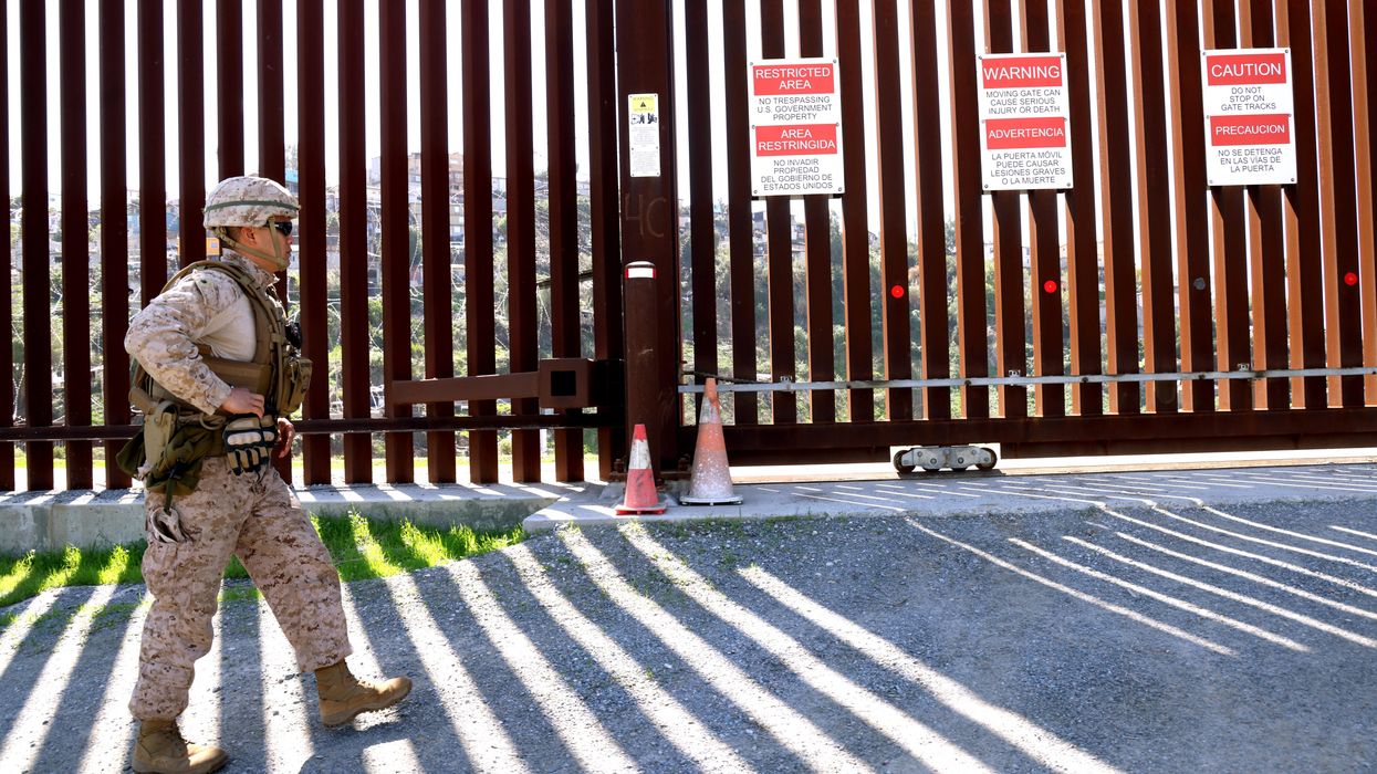 A member of the U.S. military walks along the border wall at the U.S. and Mexico border