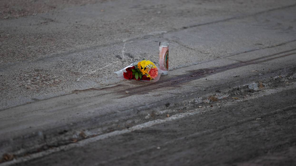 A memorial of a candle and flowers placed where a man was shot by ICE.