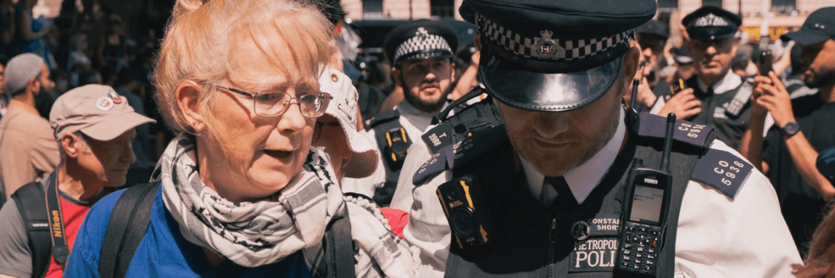 A Met Police officer arrests an elderly Palestine Action supporter