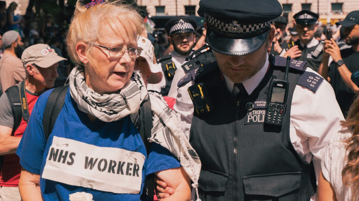 A Met Police officer arrests an elderly Palestine Action supporter