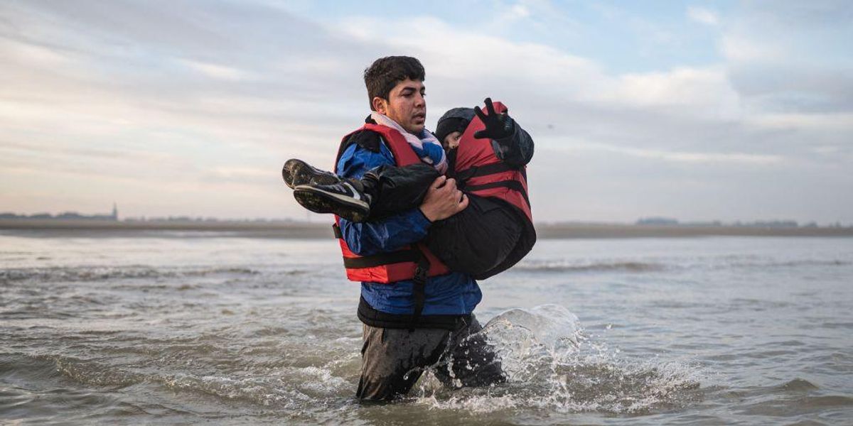 a-migrant-carries-a-child-as-he-runs-to-
