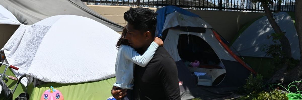A migrant man from Nicaragua embraces his daughter at a makeshift camp