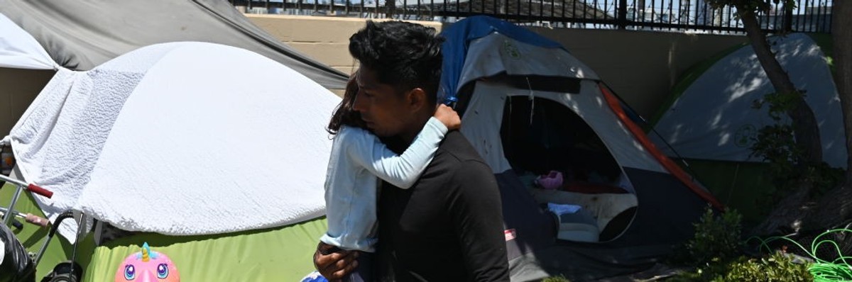 A migrant man from Nicaragua embraces his daughter at a makeshift camp