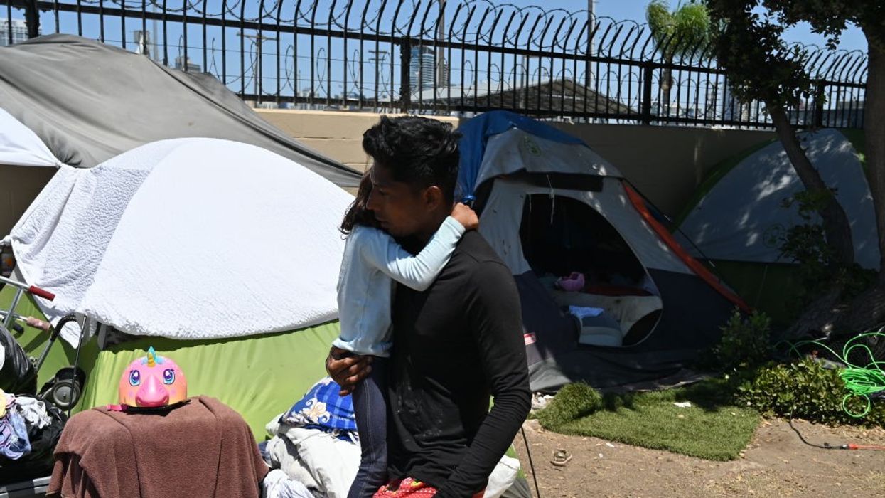 A migrant man from Nicaragua embraces his daughter at a makeshift camp