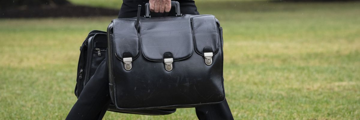 A military aide carries a black briefcase.