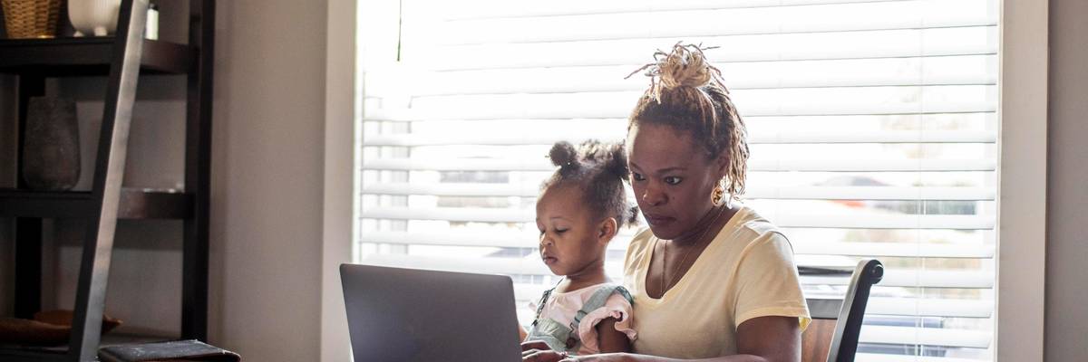 A mom works while holding a toddler