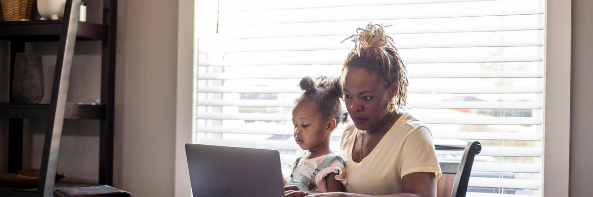 A mom works while holding a toddler