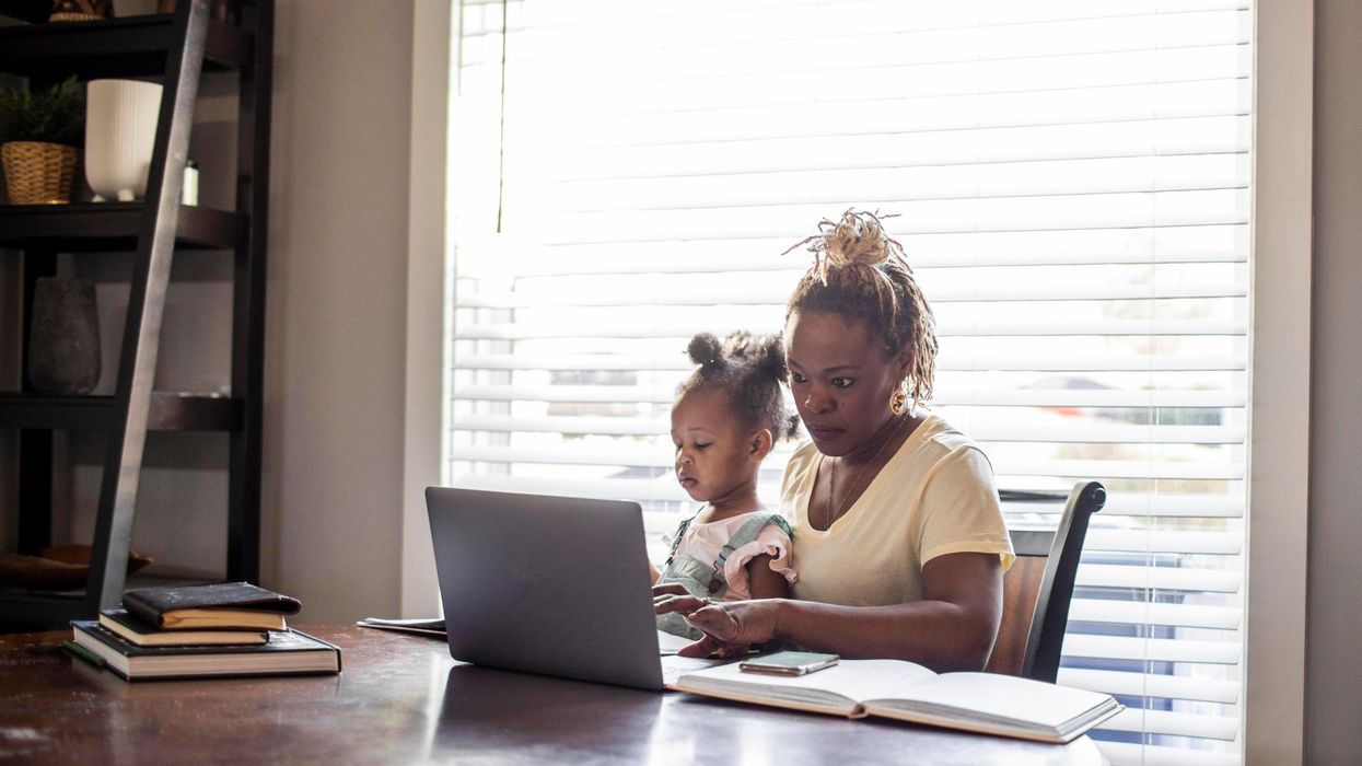 A mom works while holding a toddler