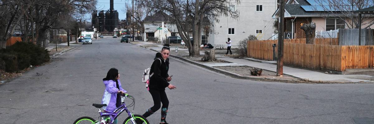 A mother and daughter walk in front of an old steel mill.