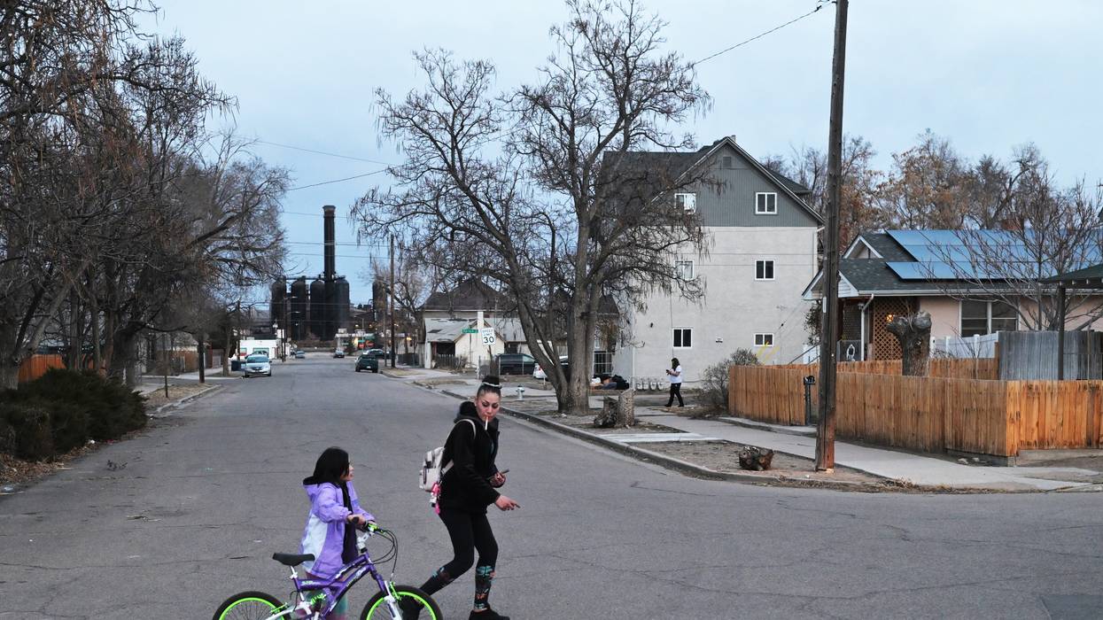 A mother and daughter walk in front of an old steel mill.