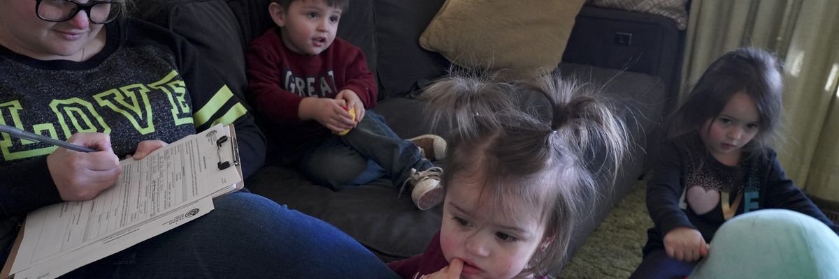 A mother fills out paperwork to enroll her kids in childcare