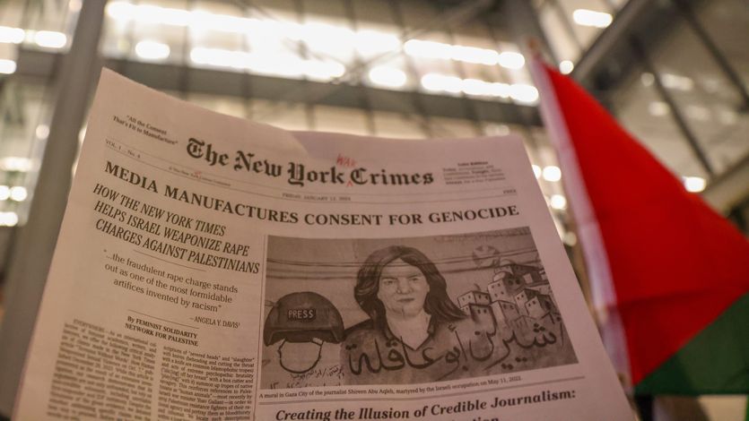 A New York Times satire paper titled New York Crimes is raised in a demonstration.