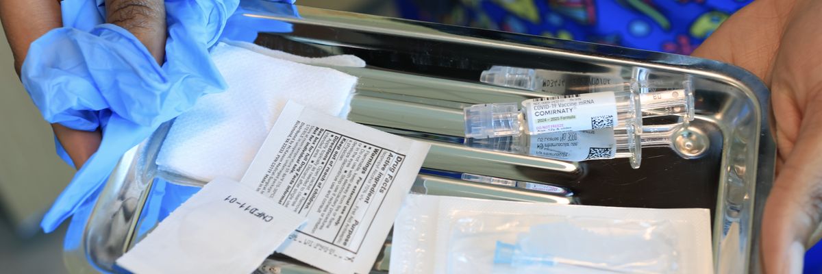 A nurse carries a tray with a Pfizer-BioNTech COVID-19 vaccine