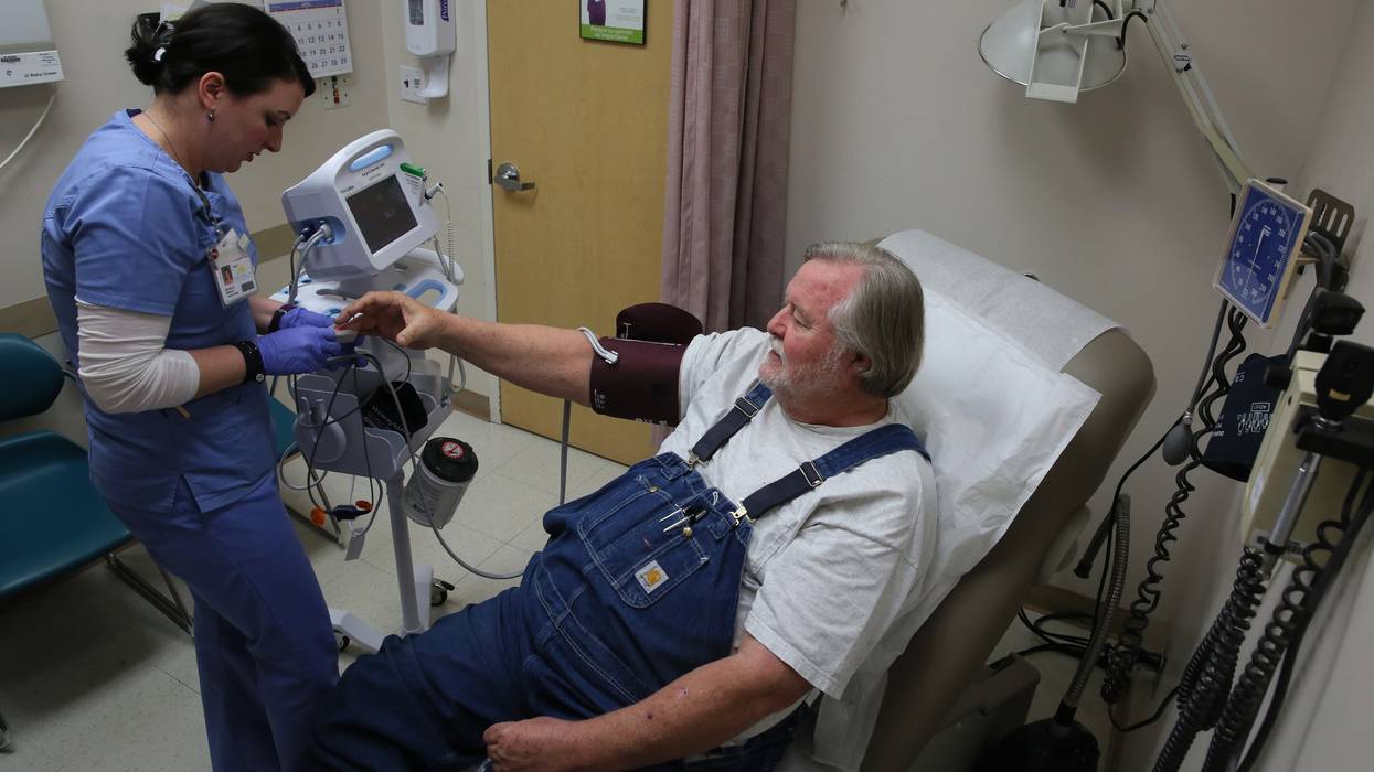 A nurse checks the blood pressure of a patient who gets health coverage through Medicare and Medicaid