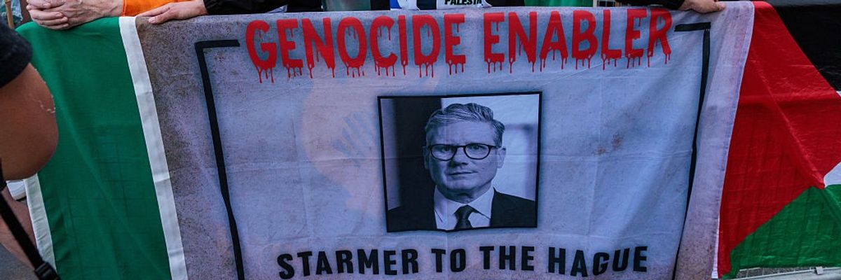 A Palestine defender holds a banner accusing U.K. Prime Minister Keir Starmer of enabling genocide