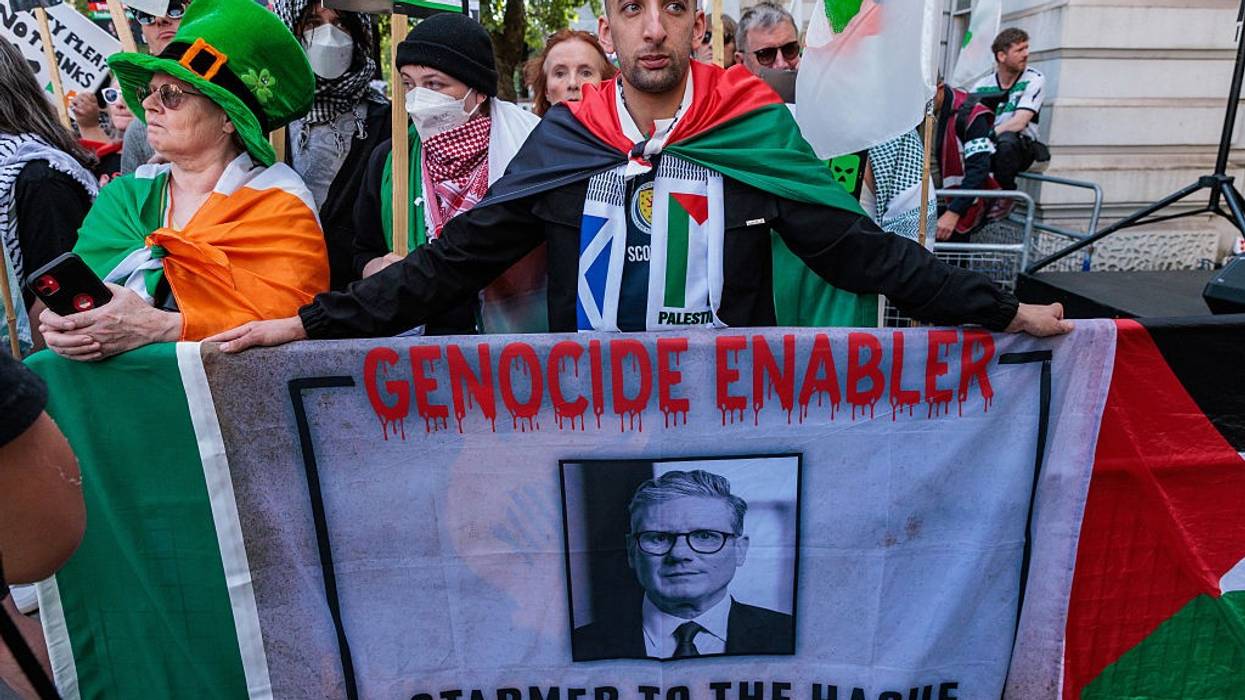 A Palestine defender holds a banner accusing U.K. Prime Minister Keir Starmer of enabling genocide