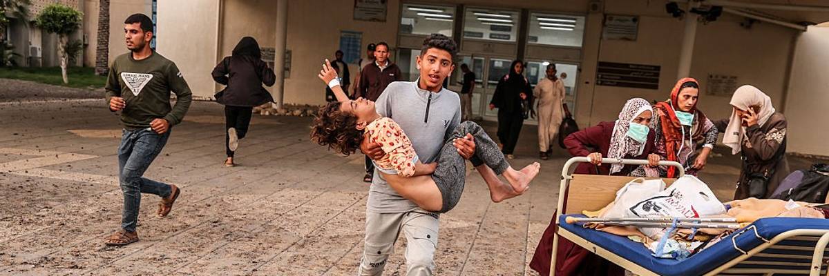 A Palestinian boy carries a child injured in an Israeli airstrike on a Gaza hospital