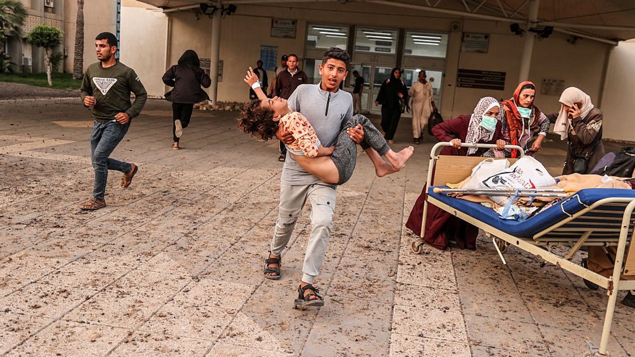 A Palestinian boy carries a child injured in an Israeli airstrike on a Gaza hospital