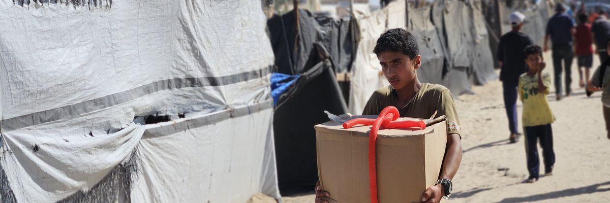 A Palestinian boy carries a food box at a humanitarian aid distribution point