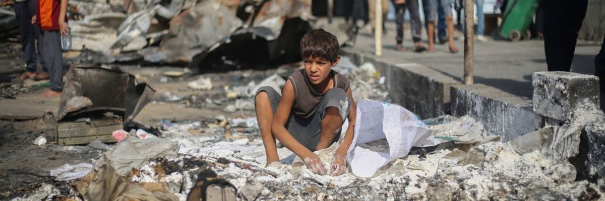 A Palestinian boy collects spilled flour from the ground