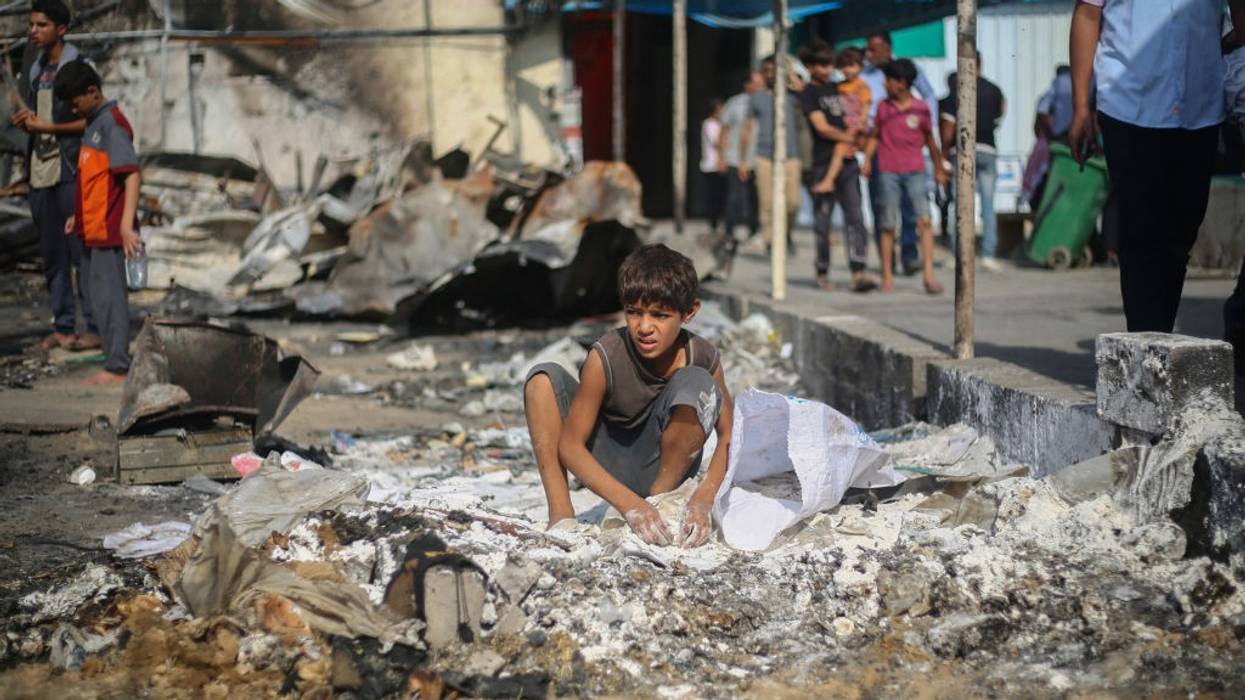 A Palestinian boy collects spilled flour from the ground