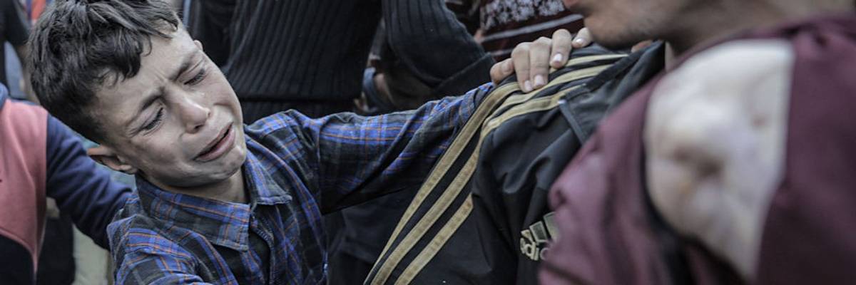 A Palestinian boy grieves as a dead infant is pulled from the rubble of their bombed home