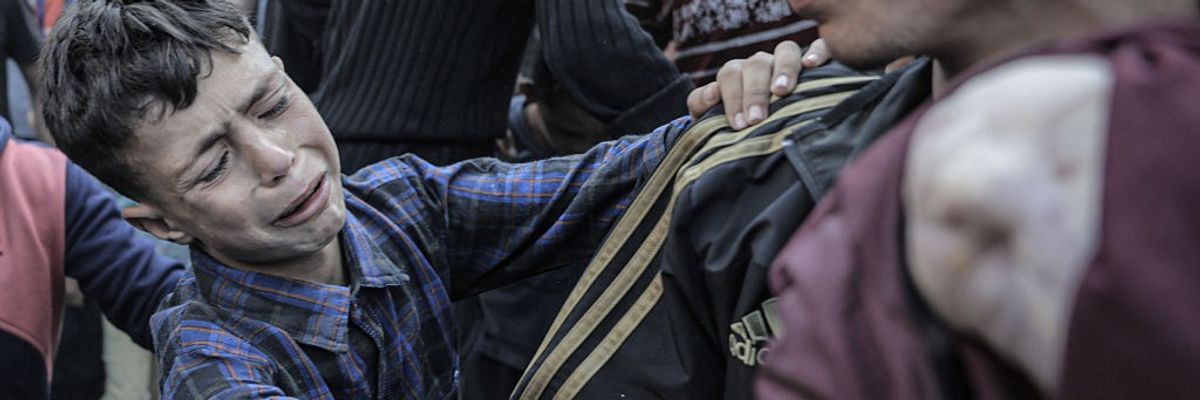 A Palestinian boy grieves as a dead infant is pulled from the rubble of their bombed home