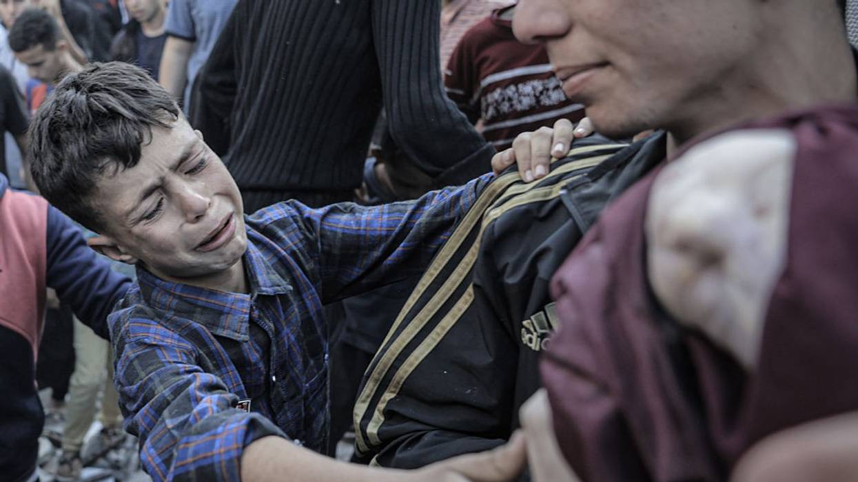 A Palestinian boy grieves as a dead infant is pulled from the rubble of their bombed home