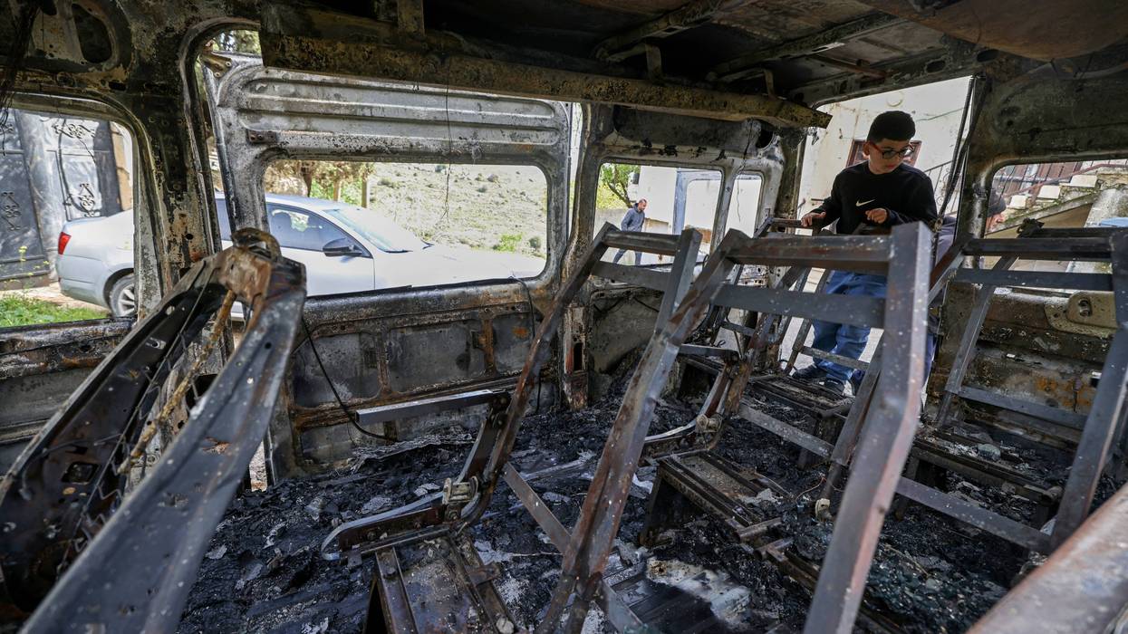 A Palestinian boy looks at a burnt vehicle in the West Bank.
