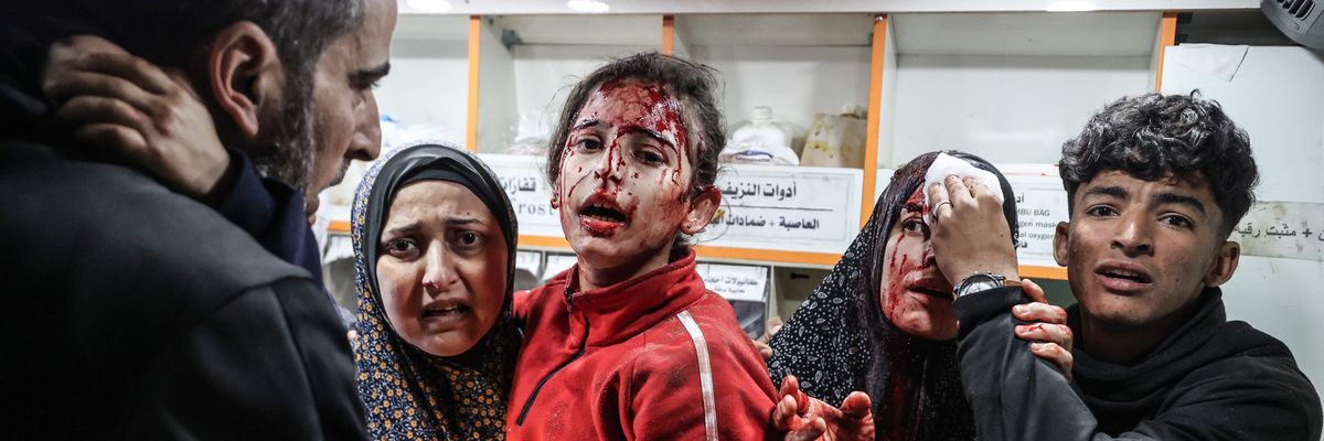A Palestinian boy puts pressure on the head of a woman injured in an Israeli attack