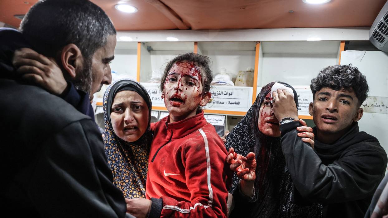 A Palestinian boy puts pressure on the head of a woman injured in an Israeli attack