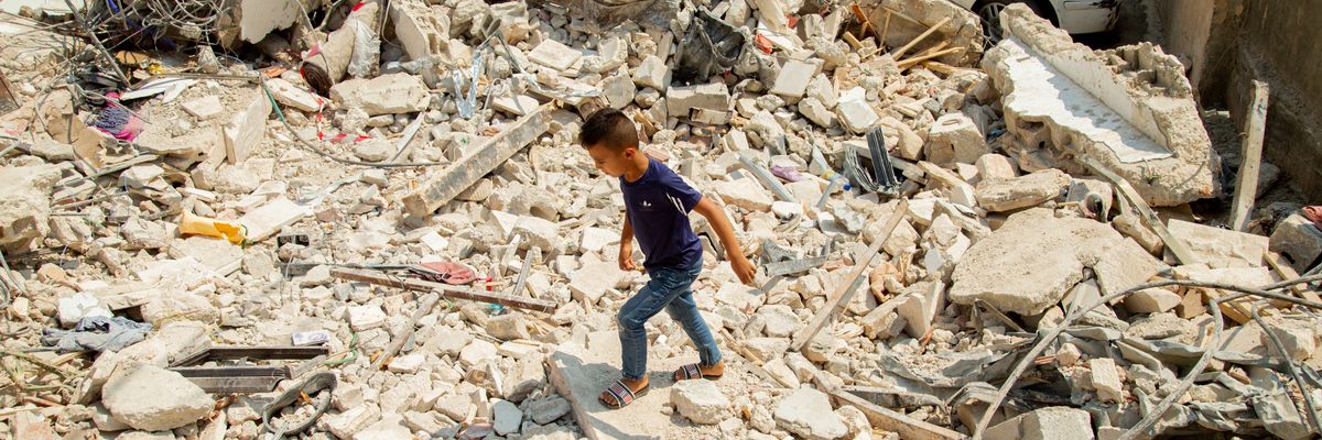 A Palestinian boy walks among houses destroyed by Israeli airstrikes