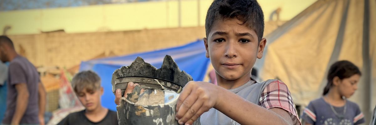 A Palestinian child holds a metal fragment