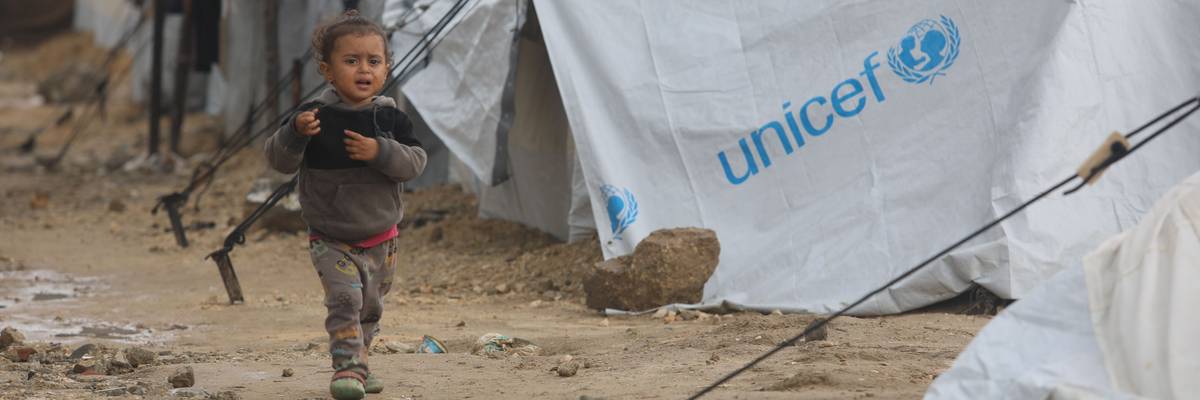A Palestinian child walks among storm-damaged tents provided by UNICEF in Gaza